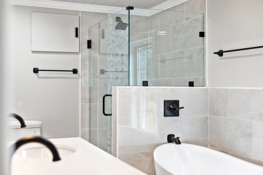 Sleek minimalist bathroom featuring a modern glass shower and elegant bathtub.